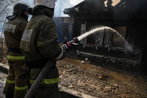 Firefighters spraying water on house