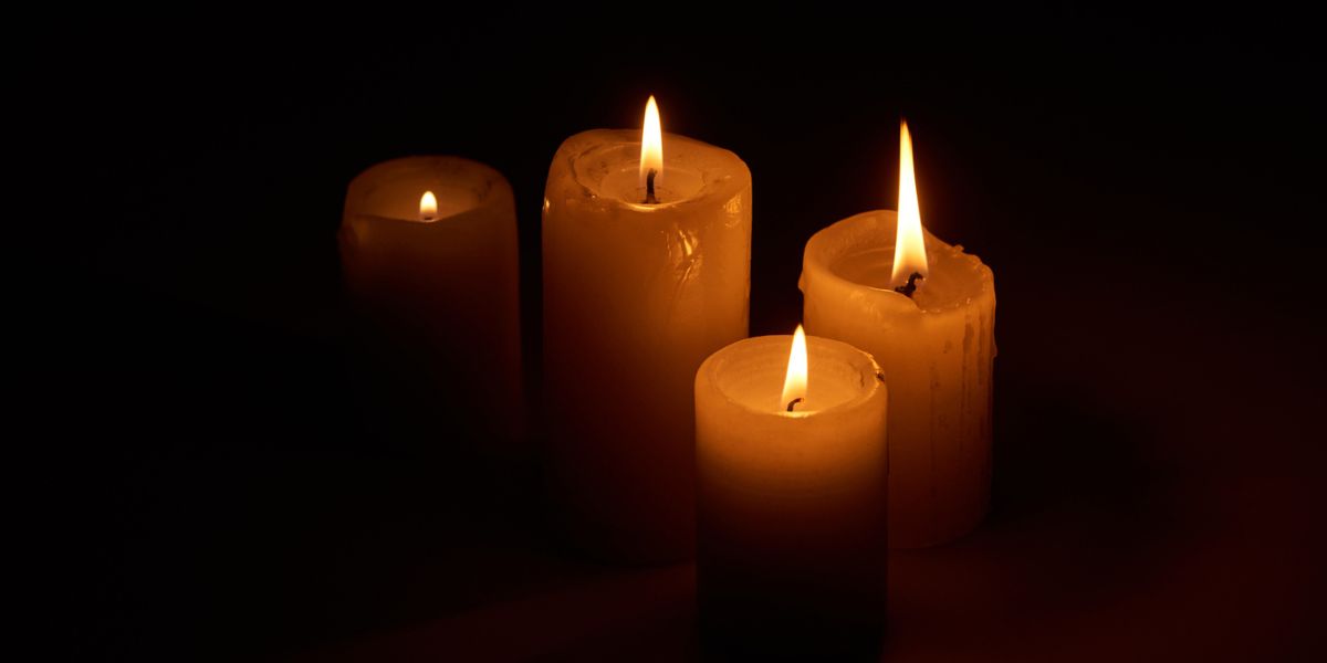 Burning candles glowing in darkness on black background