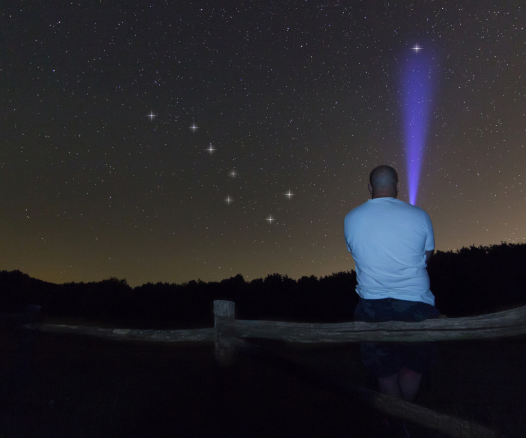 Man with a flashlight pointing to Polaris star