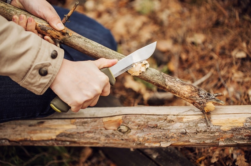 man batoning stick outdoors